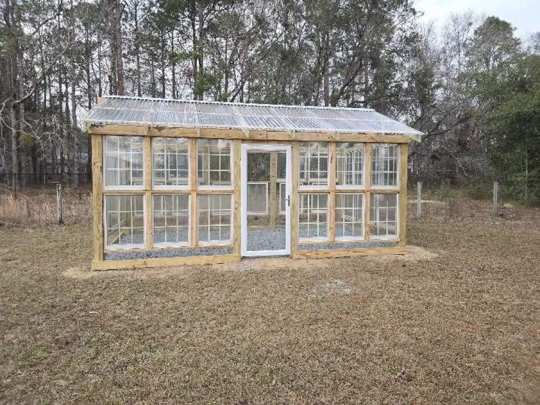 Greenhouse built from reclaimed windows with a metal roof